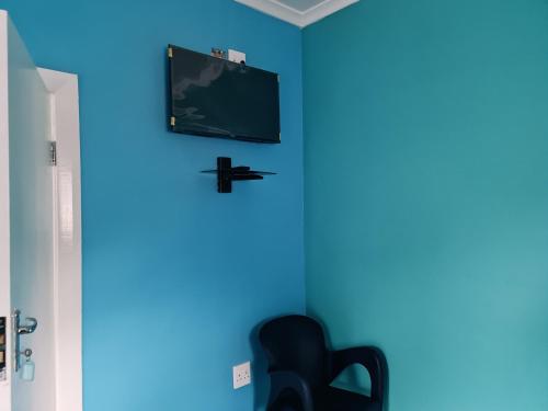 Camera blu con sedia e TV a parete di HASATE GUEST HOUSE 13 LOUWVILLE STREET BELLIVILLE Cape Town south Africa a Città del Capo