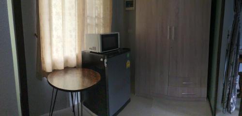 清萊的住宿－Mae Kok River Cliff Residence，客房设有一张小桌子和一台冰箱内的电视