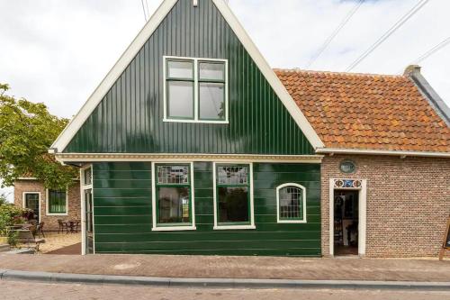 a green house with a black roof at Boutique Hotel Jongwijs Westzaan in Westzaan