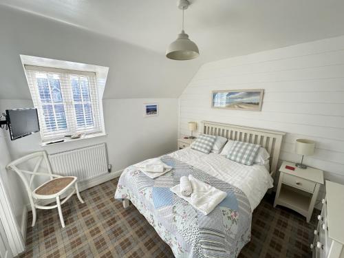 1 dormitorio con 1 cama, 1 silla y 1 ventana en Wren Cottage, en Reighton