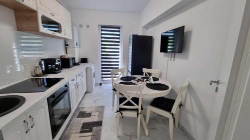 cocina blanca con mesa pequeña y sillas en Apartament Ariana Rasnov, en Râșnov