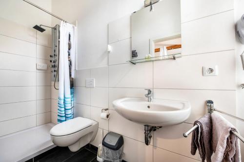 a white bathroom with a sink and a toilet at Hotel Wildeshauser Bahnhof 1 in Wildeshausen