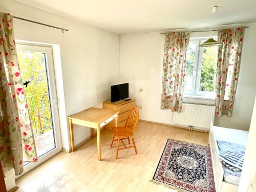 Kleines Zimmer mit einem Schreibtisch und einem TV. in der Unterkunft Gästezimmer Rothneusiedl in Wien