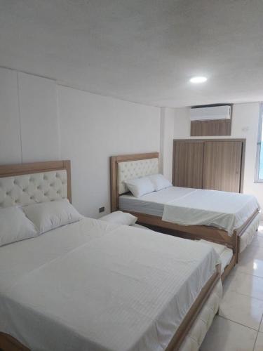 two beds in a room with white walls at MR Hermoso apartamento con vista al mar in Gaira