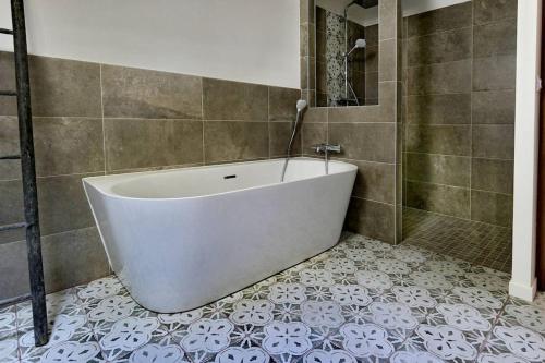 y baño con bañera blanca y suelo de baldosa. en Le Gîte - Le Pressoir en Les Molières
