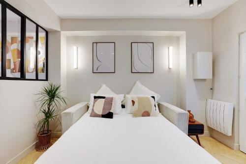 a white bedroom with a large white bed with pillows at Superbe T2 Opéra Cadet in Paris