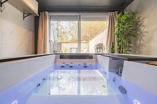 une cuisine avec comptoirs blancs et une grande fenêtre dans l'établissement Art Déco Lesage & Spa, à Reims