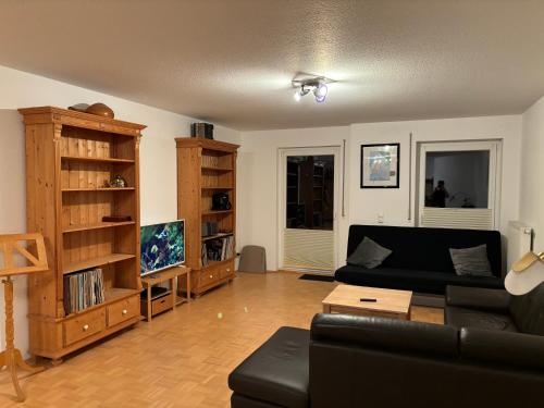 a living room with a black couch and a tv at Hübsches Apartment im Herzen Verdens in Verden