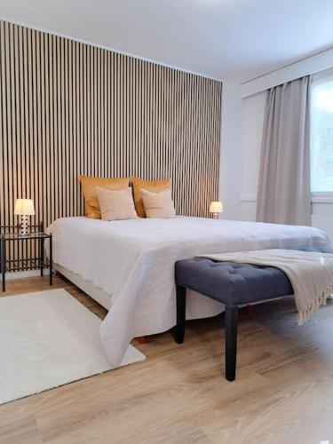 a white bedroom with a large bed with a bench at Seaside apartment in Rauma