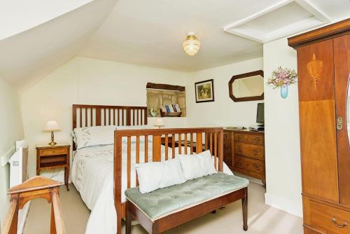 a bedroom with a bed with a bench and a dresser at Ye Olde Cottage in Niton