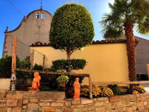 dos estatuas frente a un edificio con iglesia en Casa rural Cal Codina, en Els Prats de Rei