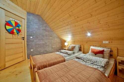 Duas camas num quarto com paredes de madeira em Domek Tworkowo Komfortowy Całoroczny em Tylmanowa