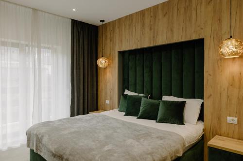 a bedroom with a large bed with a green headboard at Hotel Muntele Mic in Borlova