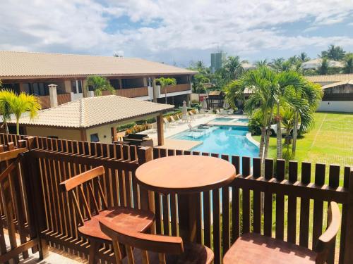 - un balcon avec une table et des chaises à côté de la piscine dans l'établissement Loft Beira Mar, à Camassari