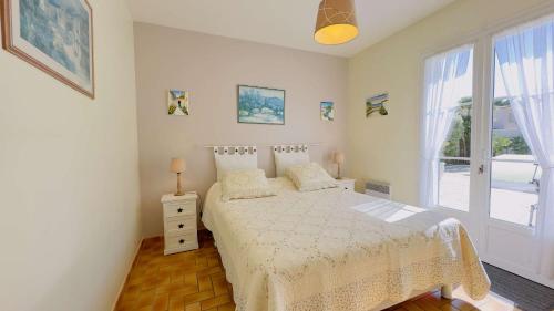 ein weißes Schlafzimmer mit einem Bett und einem Fenster in der Unterkunft Villa de plain pied avec jardin paysager et piscine in Ars-en-Ré