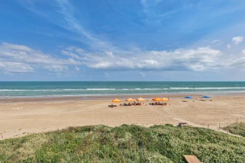 a beach with chairs and umbrellas and the ocean at First level with a secluded patio in South Padre Island