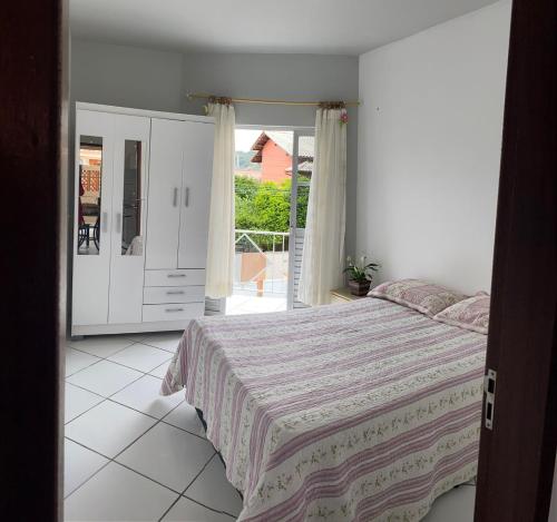a white bedroom with a bed and a balcony at Casa para temporada, Florianópolis in Florianópolis