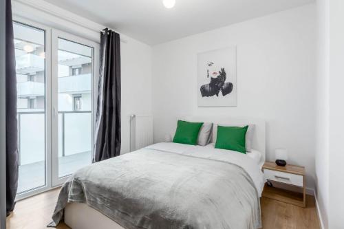 a white bedroom with a large bed with green pillows at Enjoy! Ursus in Warsaw