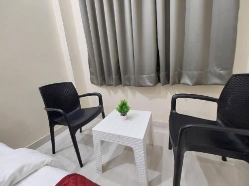 a room with two chairs and a table and a bed at HOMEWOOD SUITES Near Jaipur Airport in Jaipur