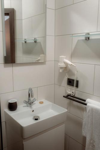 a white bathroom with a sink and a mirror at NED Hotel in Graz
