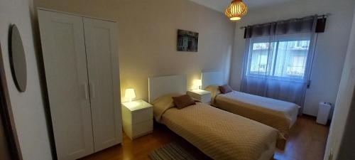 um pequeno quarto com 2 camas e uma janela em Spacious Central 2 Bedroom Apartment em Setúbal