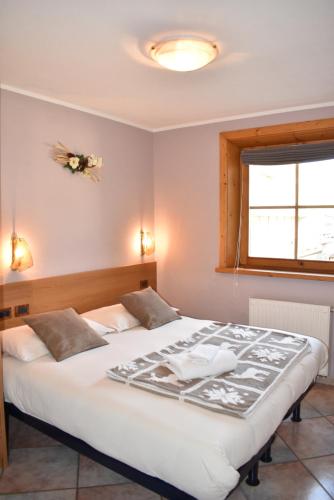 um quarto com uma grande cama branca e uma janela em Appartamento Trela 3 em Livigno