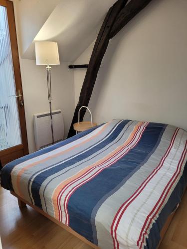 - un lit avec une couverture rayée dans une chambre dans l'établissement relais du 21, à Saint-Germain-en-Laye