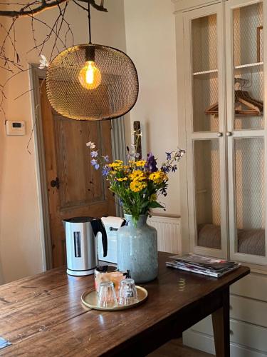 una mesa con un jarrón de flores. en B&B De Kamer Hiernaast en Gouda