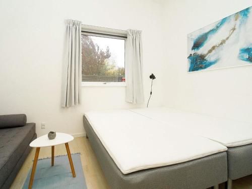 a bedroom with a bed and a couch and a window at Holiday home Gilleleje CVII in Gilleleje