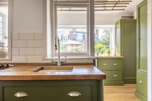 une cuisine avec des placards verts et un évier avec une fenêtre dans l'établissement Porch House, à Hunstanton