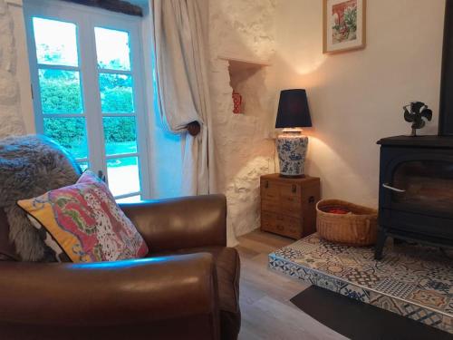 uma sala de estar com um sofá, um candeeiro e uma janela em La Petite Grange em Esse