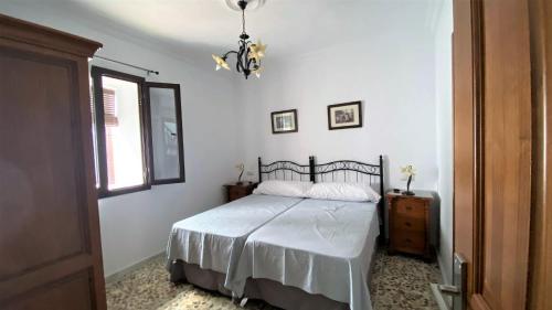 een slaapkamer met een bed, een raam en een kroonluchter bij Apartamento Doble Vacacional Carmona in Carmona