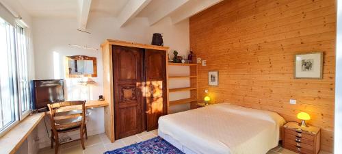 ein Schlafzimmer mit einem Bett, einem Schreibtisch und einem Fernseher in der Unterkunft Charmante villa avec piscine in La Couarde-sur-Mer