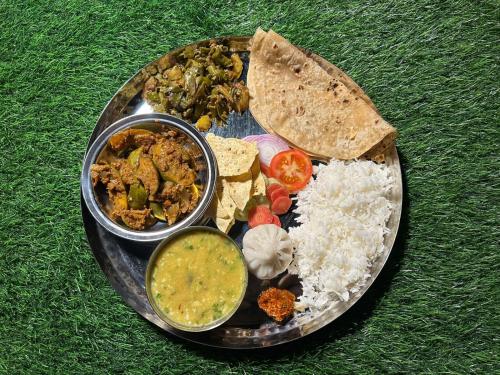a plate of food with rice and different types of food at Hrishivan Resort Nagaon in Nagaon