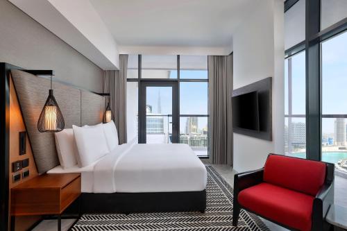 Pokój hotelowy z łóżkiem i czerwonym krzesłem w obiekcie The First Collection Waterfront w Dubaju