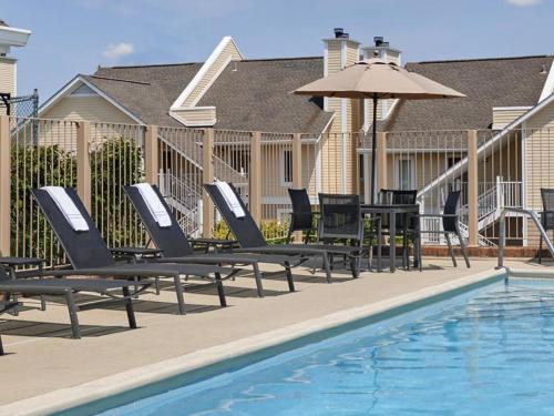 a group of chairs and an umbrella next to a pool at Sonesta ES Suites Omaha in Omaha