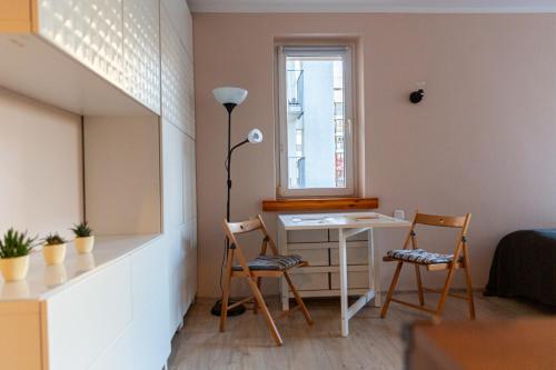 a room with a desk and two chairs and a window at Apartment Saska Kępa in Warsaw