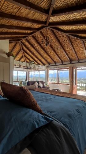 Cette chambre comprend un grand lit bleu et des fenêtres. dans l'établissement Glamping con jacuzzi Mirador Jarana Villa de Leiva, à Villa de Leyva