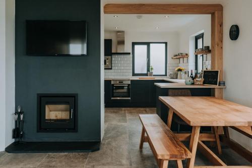 a kitchen with a fireplace and a wooden table at Unforgettable sea views, Hot tub, Modern property in Newgale