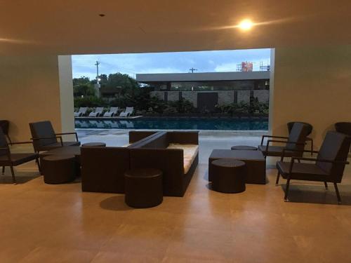a living room with a couch and chairs and a pool at Minimalist Condo Studio at Messavire Garden Residence near Ruins Bacolod in Bacolod