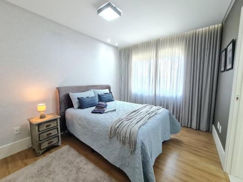 a bedroom with a bed with a night stand and a window at APT 804 - Brava Beach - 3 Quartos - 2 Vagas Garagem in Cabeçudas