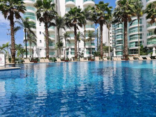 a large swimming pool with palm trees in front of a building at APT 804 - Brava Beach - 3 Quartos - 2 Vagas Garagem in Cabeçudas