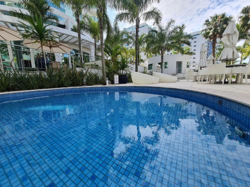 a large blue swimming pool with palm trees and buildings at APT 804 - Brava Beach - 3 Quartos - 2 Vagas Garagem in Cabeçudas