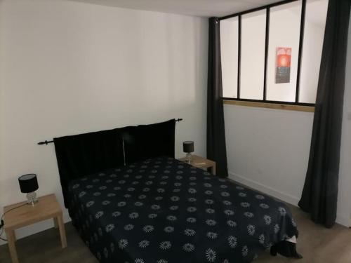 een slaapkamer met een zwart bed en een raam bij SCI la malinoise in Albon
