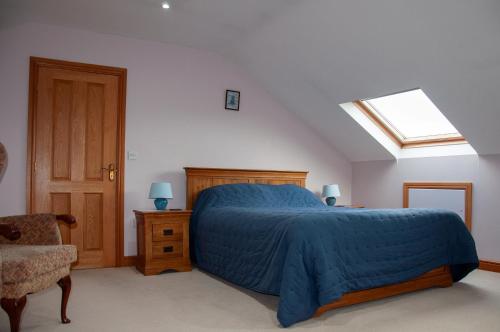 a bedroom with a bed with a blue comforter and a window at Creeghduff Lodge in Downpatrick