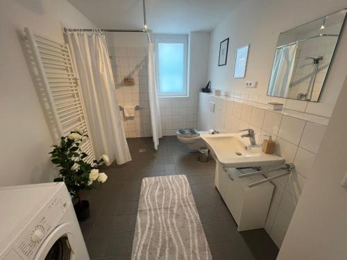 a white bathroom with a sink and a toilet at Sonnenschein Appartement in Wuppertal in Wuppertal