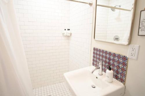 a white bathroom with a sink and a mirror at Top-Floor 2 BR in Downtown Savannah in Savannah