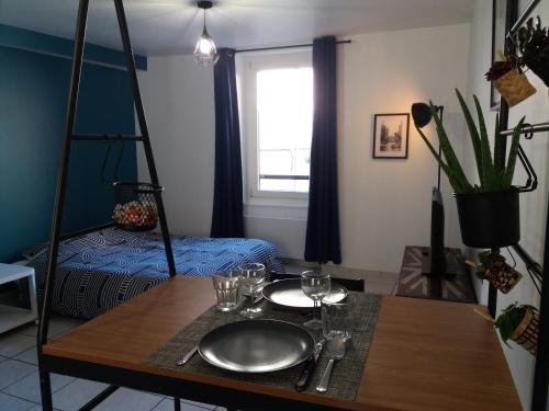 Cette chambre comprend une table avec des verres et un lit. dans l'établissement Joli studio - cœur St Marcellin, à Saint-Marcellin
