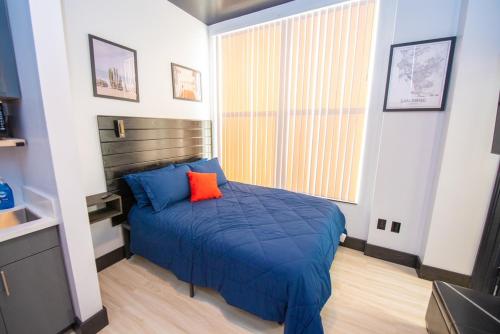 a bedroom with a blue bed with a orange pillow at Balboa Park Hotel in Downtown Little Italy in San Diego