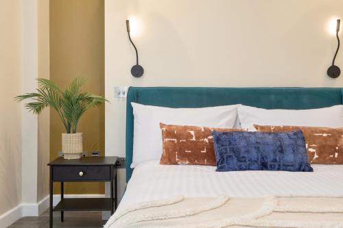 a bed with a green headboard with pillows and a plant on a table at Be London - The Chinatown Residences in London